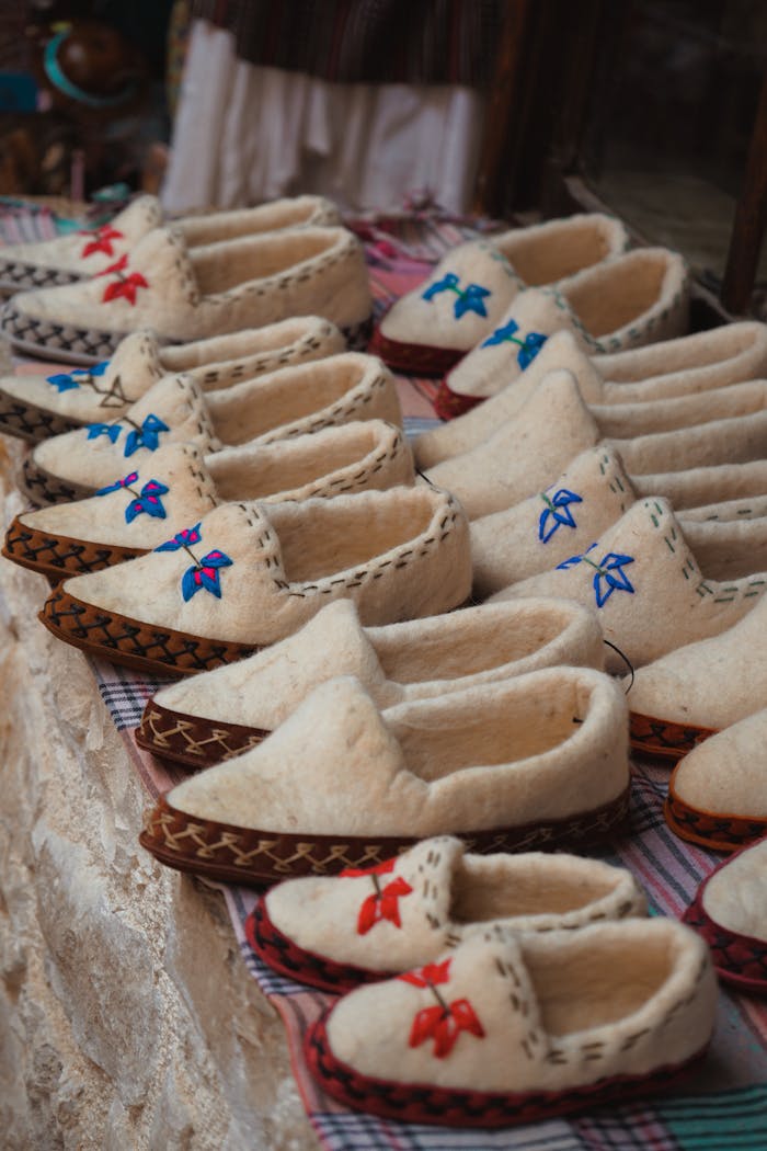 Services-03 A collection of traditional woolen slippers with colorful embroidery displayed at an outdoor market.